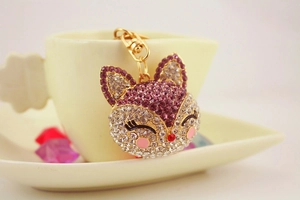 Close-up of sparkling crystal fox keychain with purple rhinestones on a golden base