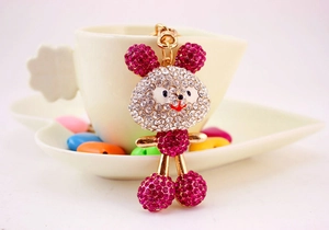 Close-up of crystal-studded mouse keychain hanging on a white coffee cup rim