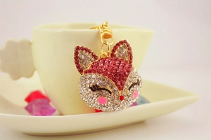 Detail of pink crystal fox keychain with rhinestones hanging on a white ceramic cup