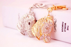 Macro detail of rhinestone-encrusted horse head keychains in gold and silver finish