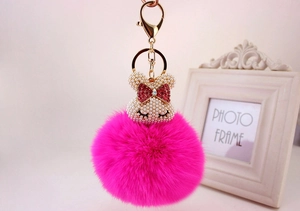 Détail du porte-clés pompon rose vif avec tête de lapin en perles et fermoir doré brillant