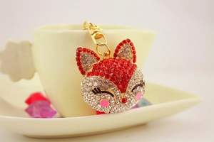 Macro view of gold fox keychain with sparkling red and white rhinestones on white cup