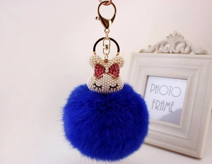 Détail du porte-clés lapin en fourrure bleue avec tête sertie de perles et nœud rouge