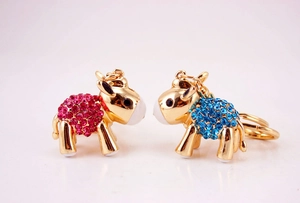 Close-up of golden sheep keychains with vibrant pink and blue crystal rhinestones