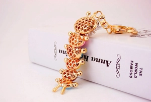Close-up of golden caterpillar keychain with hollow clover pattern and sparkling rhinestones