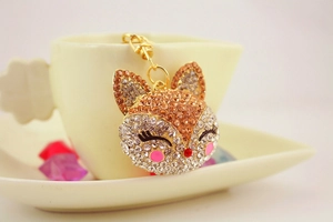 Close-up of sparkling rhinestone fox keychain with gold metal clasp on a coffee cup set