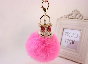 Détail d'un porte-clés pompon en fausse fourrure rose avec ours en perles et fermoir doré