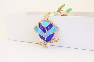 Detailed close-up of blue enamel rose pendant with rhinestones and gold-plated bow