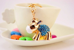 Macro shot of cute golden donkey keychain with blue rhinestones on a ceramic cup