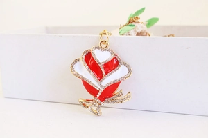 Detail shot of a rhinestone rose keychain with red and white enamel on a gold base