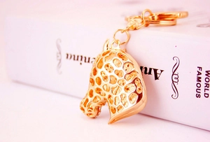 Detail of creative hollow giraffe head keychain in polished gold metal with spring clasp