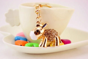 Detail of a golden donkey keychain with sparkling champagne rhinestones on a white cup