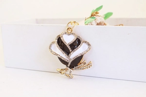 Close-up of black and white enamel rose pendant with rhinestones and gold base