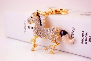 Detail of golden horse keychain featuring sparkling rhinestones and enamel accents