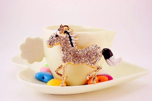 Detail of crystal rhinestone horse keychain with white enamel mane and golden metal frame