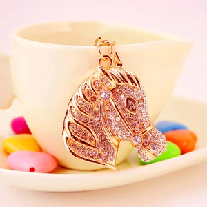Creative rose gold rhinestone horse head keychain pendant hanging on a white ceramic cup