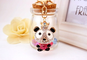 Close-up of sparkling rhinestone panda keychain with a golden crown on floral background