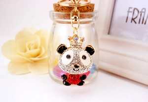 Close-up of sparkling rhinestone panda keychain with gold crown on a gift background