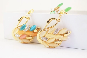 Close-up of rhinestone swan keychain with gold alloy finish and colorful resin wings