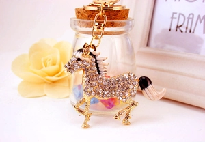 Close-up of golden horse keychain with sparkling rhinestones and enamel details