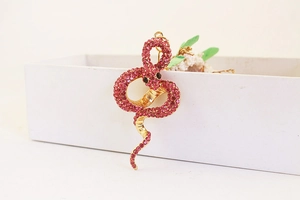 Détail d'un porte-clés serpent doré serti de strass roses brillants et yeux noirs discrets