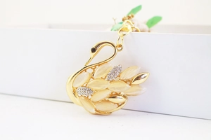 Macro detail of golden swan keychain with opal stones and sparkling rhinestone crystals