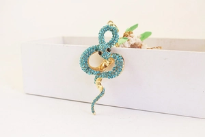 Détail d'un porte-clés serpent avec strass bleu clair sur un support en alliage doré