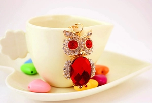 Detail of cute owl keychain with red crystal body and white rhinestones on gold metal