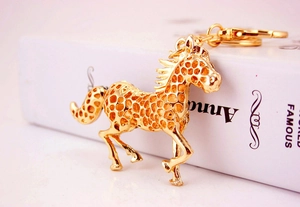 Detailed view of a gold hollow horse keychain with honeycomb texture on a white book