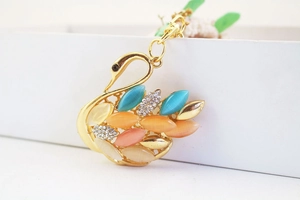 Detailed macro view of gold swan charm with colorful opals and sparkling rhinestones