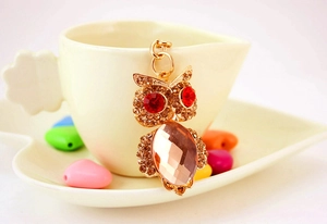 Close-up of sparkling crystal owl keychain with red rhinestone eyes and gold plating
