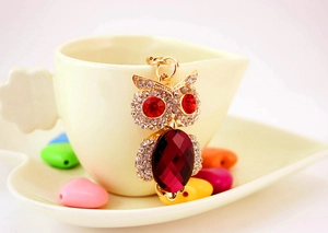 Detail of owl keychain with sparkling white crystals and large ruby red gemstone belly