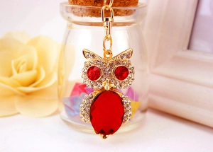 Macro detail of golden owl keychain with sparkling white crystals and large red gemstones