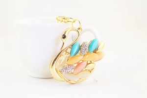 Detailed macro view of gold swan keychain with colorful cat eye stones and rhinestones