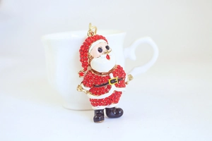 Détail d'un pendentif Père Noël en strass rouges sur une tasse en céramique blanche