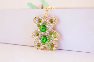 Dettaglio portachiavi a forma di orso dorato con cristalli verdi smeraldo e strass bianchi