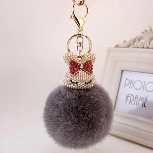 Porte-clés lapin en peluche grise avec tête de perle et nœud en strass rouge brillant