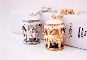 Détail des porte-clés carrousel avec émail blanc et strass brillants sur métal