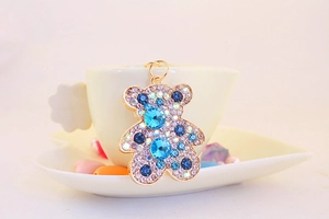 Dettaglio di un portachiavi a forma di orsetto con strass su una tazza bianca