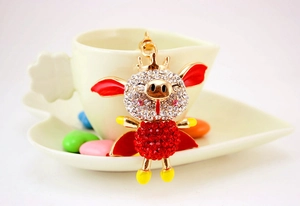 Détail du porte-clés cochon volant doré avec strass rouges et blancs étincelants