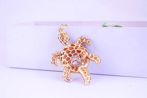 Détail d'un porte-clés tortue dorée avec une coque évidée et des cristaux brillants sertis
