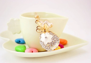 Gros plan du porte-clés sac à fleurs en strass doré sur un rebord de tasse
