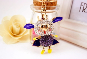 Détail du porte-clés cochon volant serti de strass avec couronne et ailes violettes