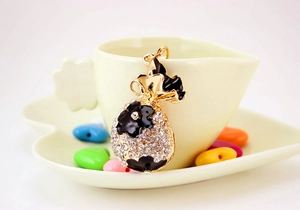 Détail d'un porte-clés sac à main doré avec fleurs en strass sur une tasse à café