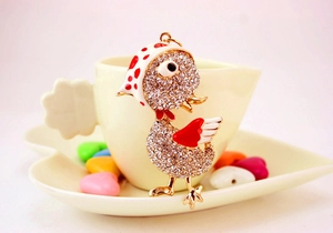 Détail d'un porte-clés canard en strass avec ailes en émail sur le bord d'une tasse à café