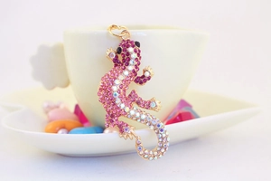 Gros plan d'un porte-clés lézard orné de cristaux roses et violets sur le bord d'une tasse
