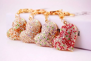 Dettaglio di portachiavi a cuore con cristalli colorati, placcatura in oro e moschettoni