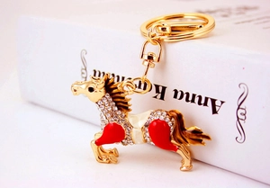 Close-up of golden horse keychain with white rhinestones and red enamel detail