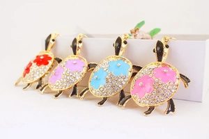 Vue détaillée des porte-clés tortue ornés de strass et de motifs floraux en émail coloré