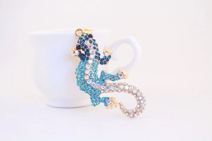 Détail d'un porte-clés lézard avec cristaux bleus et blancs sur une tasse blanche